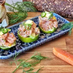 Delicioso tartar de salmón y aguacate servido en mitades de lima, decorado con jalapeño y eneldo.