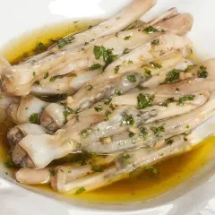 Navajas a la plancha con ajo y perejil, servidas en un plato blanco con aceite dorado.